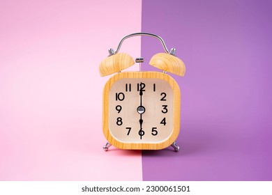 Vintage houten wekker op een roze en paarse achtergrond.