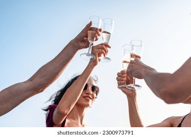 Friends group drink a champagne at outdoor party on yacht. Attractive young men and women hanging out, happy fun to celebrating holiday vacation trip on catamaran sailing boat, Summer relaxation time