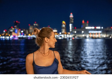 Wanita muda di atas bot dengan latar langit Cleveland yang diterangi di latar belakang.