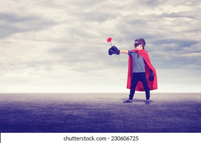 Superhero kid wearing boxing gloves and flower outdoors.
