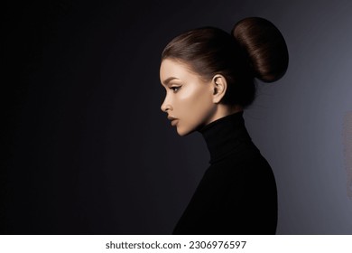 Potret studio seni fesyen wanita cantik elegan dengan turtleneck hitam. Rambut rasuk tinggi, wajah profil sempurna. Gaya kecantikan yang elegan. Anting-anting di telinga