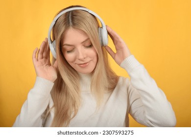 cute young blonde woman enjoying music in headphones