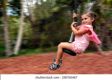 Young girl (female age 04) rids on zip line flying fox outdoor game play equipment in a children's playground.