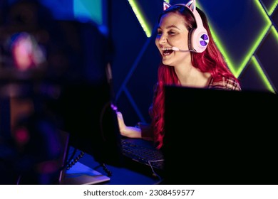 Donna felice che urla di gioia mentre domina un eSport, celebrando la sua vittoria in un gioco online. Con una telecamera installata per registrare le sue tecniche di gioco, condivide la sua esperienza in un live streaming.