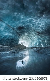 Landscape view of a silhouette reflecting in the melting ice of an ice cave in Furgg glacier in Zermatt, with blue shades and textures