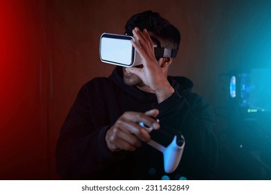 ผู้ชายในห้องมืด วิดีโอเกมพร้อมแว่น VR และคอนโทรลเลอร์ สตรีมมิ่งออนไลน์พร้อมเกมและเมตาเวิร์ส โลกดิจิทัล สตรีมเมอร์ชายและเทคโนโลยีแห่งอนาคตพร้อมประสบการณ์เกมและความเป็นจริงเสมือน