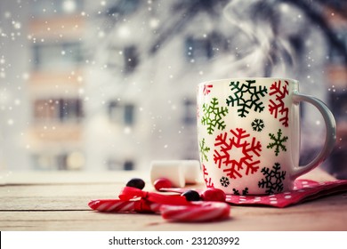 Heiße Kaffeetasse auf einem frostigen Wintertag Fensterhintergrund mit Zuckerstangen / Weihnachtsferien Hintergrund / Winter gemütlicher Hintergrund