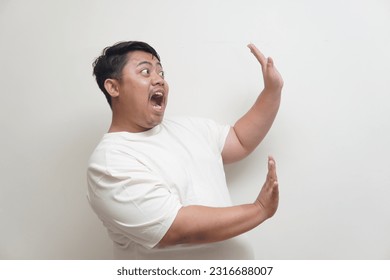 Retrato de un hombre asiático haciendo un gesto con la mano para evitar algo. Imagen aislada sobre fondo blanco