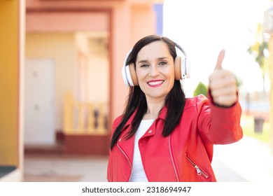 音楽を聴きながら親指を立てている中年女性