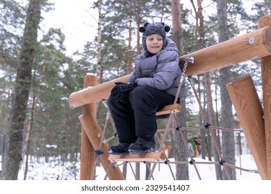a happy boy is playing on a children's playground in a winter park. children's entertainment and outdoor games. High quality photo