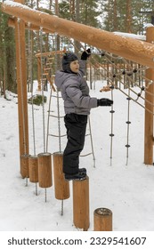 a happy boy is playing on a children's playground in a winter park. children's entertainment and outdoor games. High quality photo