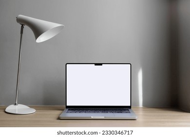 الكمبيوتر المحمول موجود على سطح المكتب على خلفية رمادية في الفندق. يوجد بالقرب منه كرسي، وهو مكان لوضعه في الشاشة