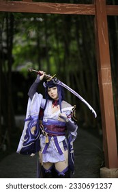Portret i një loje të re të bukur cosplay me kostum fustan samurai në kopshtin japonez