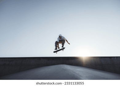 Drsalec izvaja kickflip na rampi v skate parku - Eleganten skaterboy trenira zunaj - Koncept ekstremnega športnega življenjskega sloga
