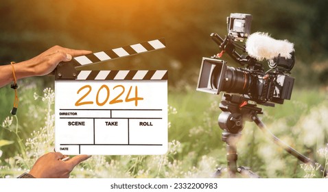 2024 - مكتوب بخط اليد على لوحة الفيلم. طاقم الفيلم يحمل لوحة الفيلم وكاميرا يصورون فيلمًا في الخلفية الخارجية. لمحتوى المبدعين في العام الجديد 2024