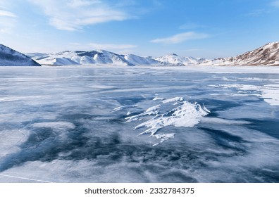 晴れた寒い日に凍ったバイカル湖の美しい冬の風景。雪に覆われた海岸の丘と山々が凍った浅い湾を囲んでいます。自然の季節の背景、環境