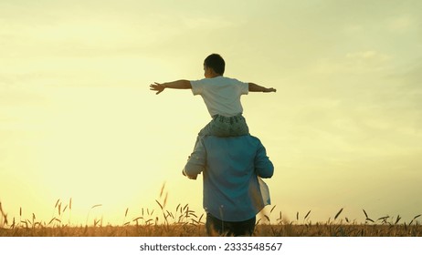 Bapa berlari dengan anaknya di bahunya, ladang gandum, matahari terbenam. Ayah, anak bersama-sama Berjalan di padang, permainan yang menyeronokkan. Keluarga bahagia. Ayah petani bermain dengan anaknya di luar rumah. Impian kanak-kanak untuk terbang, anak superhero