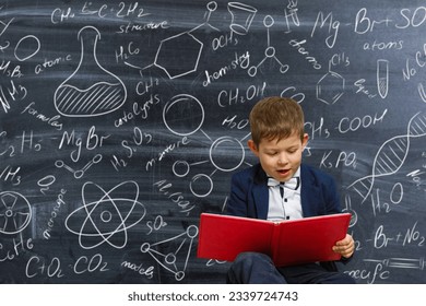 Retrato de um garotinho inteligente em uniforme escolar no fundo de um quadro negro com fórmulas científicas e diagramas. Crianças inteligentes. Educação.