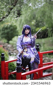 Portret i një loje të re të bukur cosplay me kostum fustan samurai në kopshtin japonez