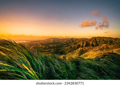 Eine idyllische Landschaft mit einem wunderschönen Sonnenuntergang über einer Bergkette, üppigem Gras und leuchtenden Farben, Guam