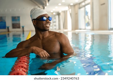 Athlète masculin joyeux debout dans la piscine sportive
