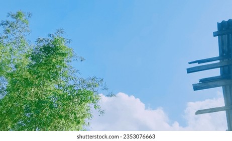 Die wunderschöne Landschaftsansicht mit Bambusbäumen, Dächern, Wolken und blauem Himmel. Der Anime-Stil der malerischen Landschaft.