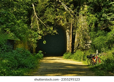 On a sunny summer day, a red bike rests against a mileage marker at the entrance to one of three tunnels on the Elroy-Sparta State Trail.