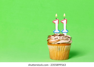 Biglietto di auguri di compleanno con cupcake e candela numero 11; foto su sfondo verde.