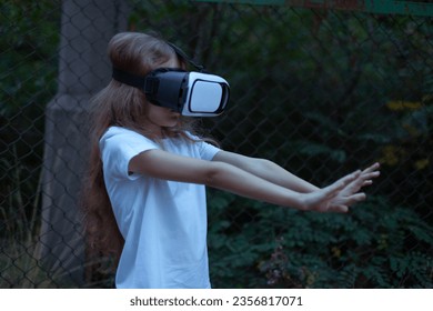 Girl child in virtual reality glasses plays a horror game at night.