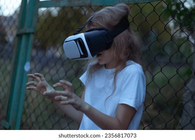 Girl child in virtual reality glasses plays a horror game at night.