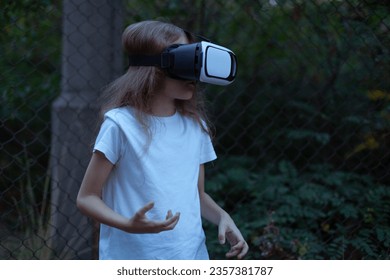 Girl child in virtual reality glasses plays a horror game at night.
