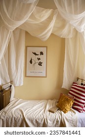 canopy over vintage bed. vintage iron bed in a room with yellow walls.