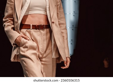 Figur einer Mode-Model-Frau in beigefarbenem, elegantem Freizeitkostüm, Hose und Jacke auf schwarzem Hintergrund. Stilvolle Modeaufnahme. Streetstyle-Kleidungskonzept