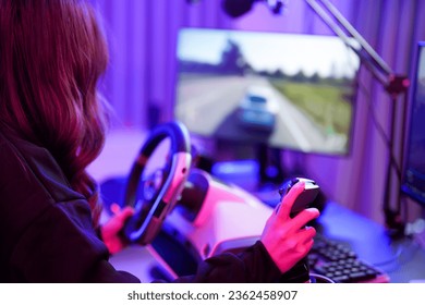 エンターテイメント ネオン ゲーマー ルームで、ステアリング ホイールとギア コントローラー シミュレーション ガジェットのクローズアップ ハンドとモニター スクリーンを使用して、スーパー スピード カー ゲームをプレイするアジアの若い 10 代のドライバーの女の子