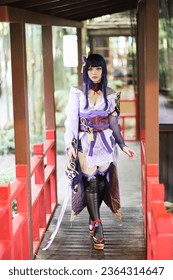 Portret i një loje të re të bukur cosplay me kostum fustan samurai në kopshtin japonez