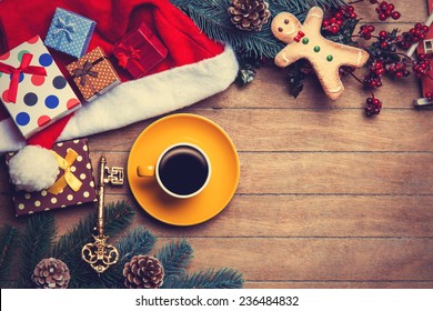Cup of coffee with pine branch and christmas gifts on wooden background.