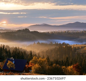 L'aria. Nebbia mattutina e primi raggi di sole sui pendii autunnali dei Monti Carpazi e una fattoria irriconoscibile (Ucraina).