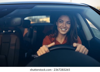 Happy woman driving a car and smiling. Cute young success happy brunette woman is driving a car. Portrait of happy female driver steering car with safety belt