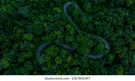 Vue aérienne d'une route dans une forêt avec un flou de mouvement en voiture. Route sinueuse à travers la forêt. Conduite en voiture sur la route entre une forêt verte. Écosystème, environnement sain, voyage sur la route.