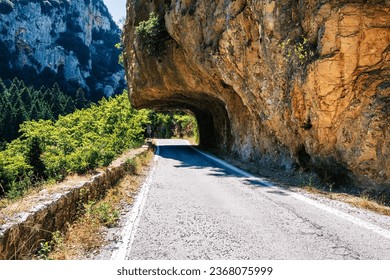 The gorgeous road under the rocks in the old Sparta-Kalamata highway in Peloponnese, Greece. This road connects two historic cities, Sparta and Kalamata, and offers breathtaking views of the Taygetos.