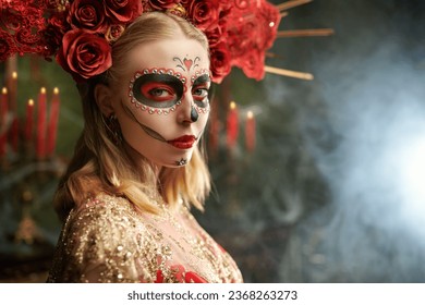 La hermosa Santa Muerte con un vestido festivo de color rojo dorado y un tocado floral se encuentra en el antiguo castillo. Día de los Muertos. Chica con calavera de azúcar. Halloween. Día de los Muertos.