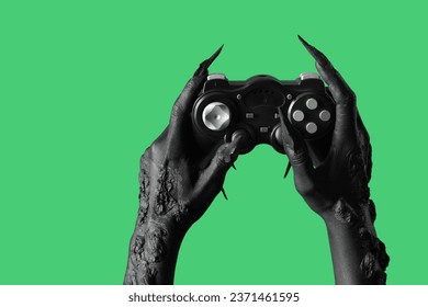 Black hands of witch with game pad on green background. Halloween celebration