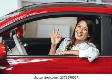 Người phụ nữ hạnh phúc lái xe với ngón tay cái hướng lên. Cô gái xinh đẹp nhìn qua cửa sổ xe và tỏ vẻ ổn. Người phụ nữ kinh doanh qua cửa sổ xe tỏ vẻ ổn