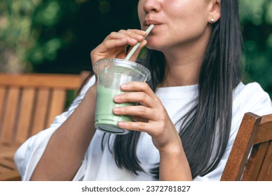 Wanita minum matcha latte, minuman dingin yang menyehatkan.