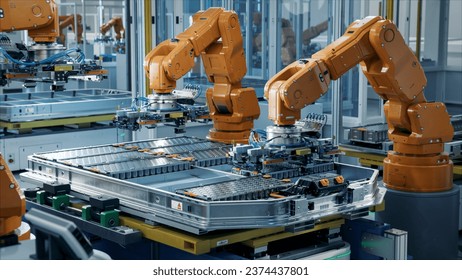 Orange Industrial Robot Arms Assemble EV Battery Pack on Automated Production Line. Row of Advanced Robotic Arms inside Automotive Plant Assemble Batteries. Modern Electric Car Smart Factory.