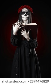 Người phụ nữ trẻ trang điểm bằng calavera (đầu lâu đường) cầm cuốn sách (grimoire) trên tay. Cô gái phù thủy với lớp sơn mỡ muertos (muerte) trong chiếc váy đen. Chủ đề Ngày của người chết (và Halloween)