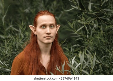 Umělecký elf muž s červenými vlasy a zelenýma očima v lese.