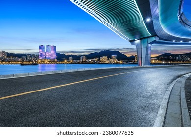 Jalan asfalt dan jambatan dengan pemandangan latar langit bandar pada waktu malam