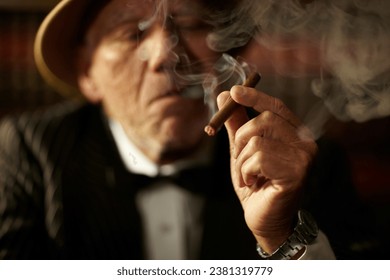 老人，手里拿着烟，抽着烟，黑帮头目做出了决定。黑手党或乡村俱乐部里的黑帮、脸和抽着老式雪茄的老人，有奢侈、恶习或习惯