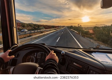 Vista dal posto di guida di un camion dell'autostrada e di un paesaggio di campi all'alba.